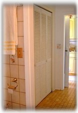 Closet space and bath with tiled shower and sink.