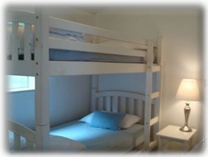 The second bedroom has three twin beds: a single twin bed and bunkbeds.